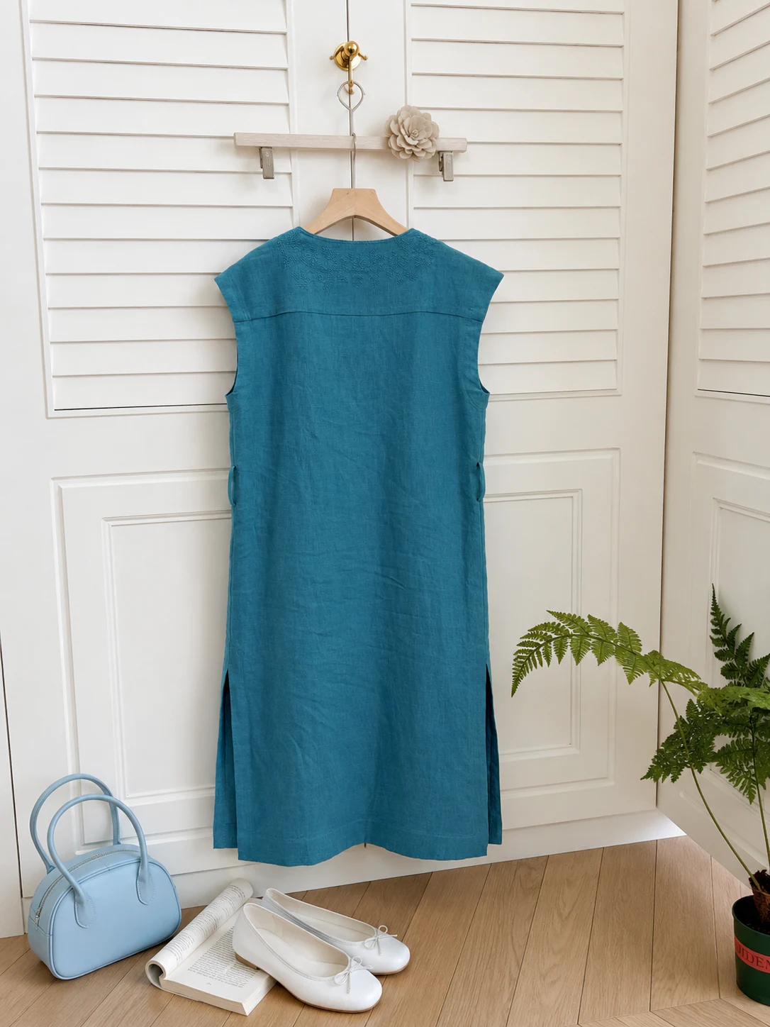 Turquoise-green sleeveless dress hanging against white paneled doors